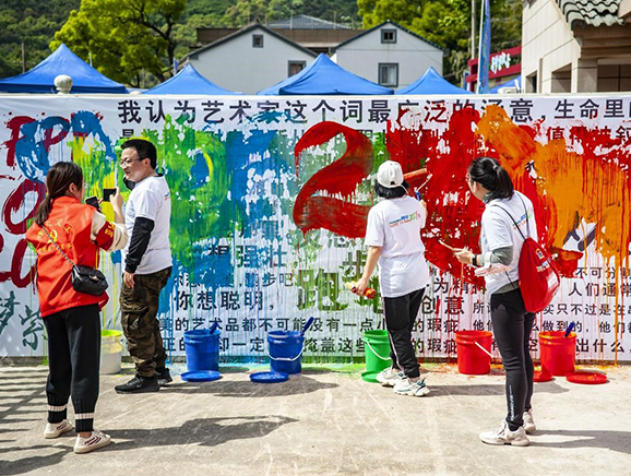 福民村写生基地举办了青年艺术展，参与活动人员在海报上涂鸦
