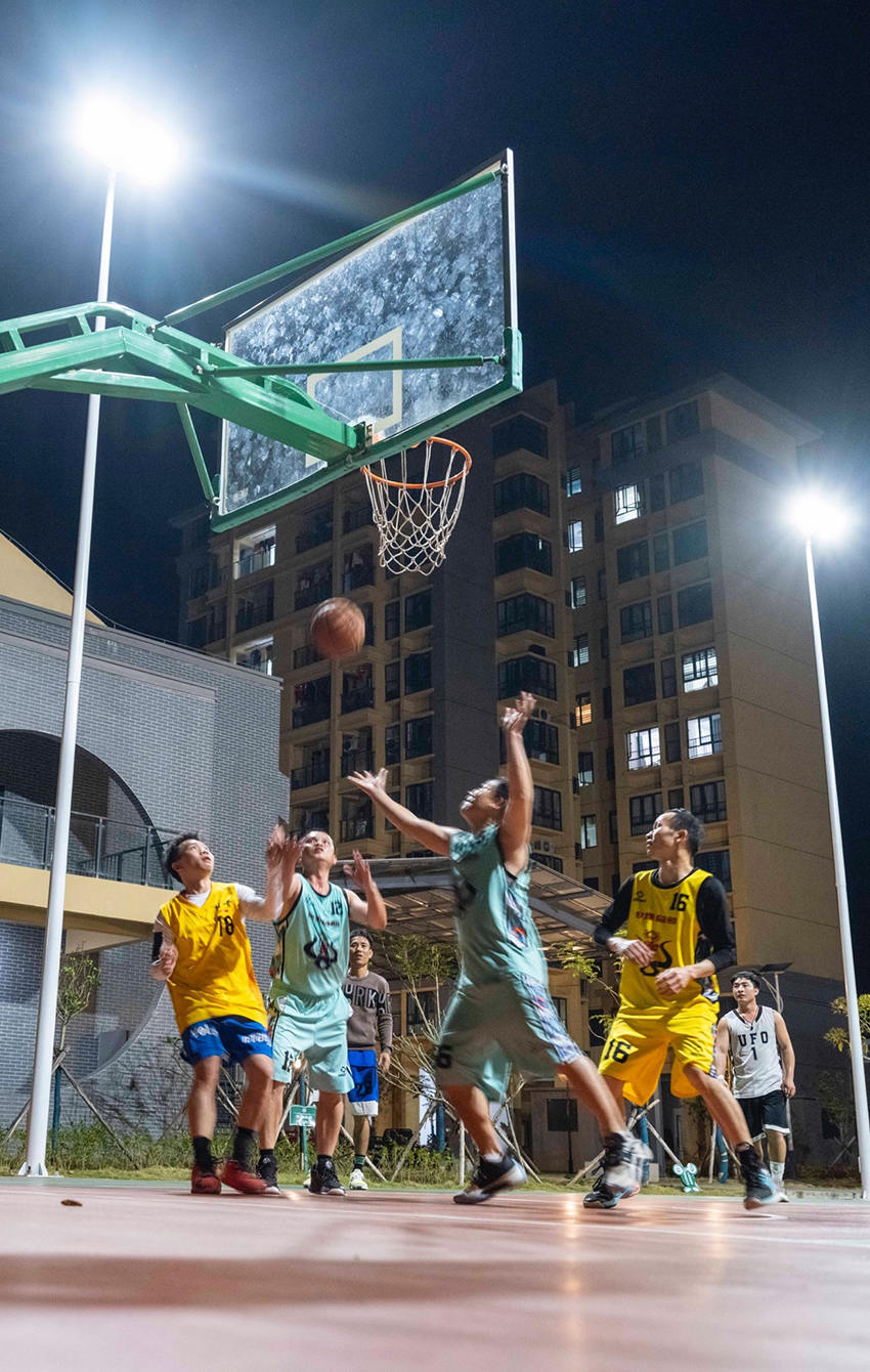 2023年3月，五指山市龙庆新村。下班后，年轻人喜欢在小区篮球场打球。澎湃新闻记者 许海峰 图
