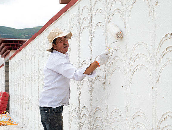 2023年7月，工人在塔巴村粉刷民宿的墙壁。